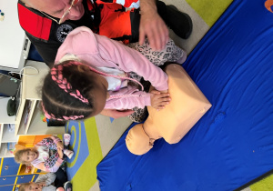 Dziecko z ratownikiem układa dłonie na fantomie.