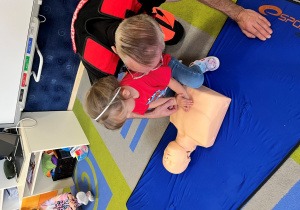 Dziecko z ratownikiem układa dłonie na fantomie.