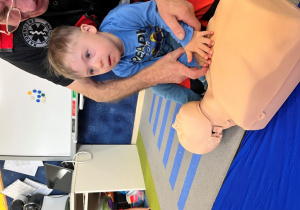 Dziecko z ratownikiem układa dłonie na fantomie.