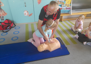 Dziewczynka ćwiczy na fantomie masaż serca.