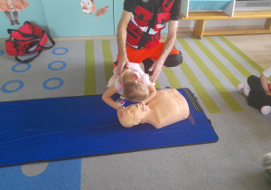 Dziewczynka sprawdza na fantomie czy osoba oddycha.