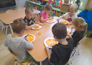 Dzieci malują farbą talerzyki papierowe.