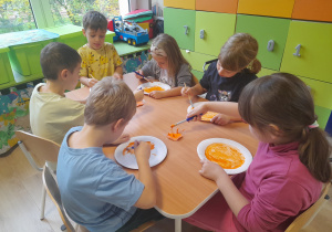 Dzieci malują farbą talerzyki papierowe.