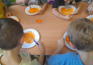 Dzieci malują farbą talerzyki papierowe.