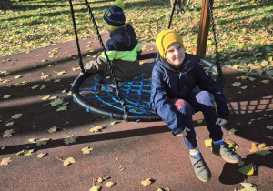 Chłopcy siedzą na huśtawce.