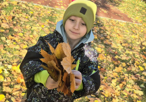 Chłopiec z bukietem pięknych, jesiennych liści.