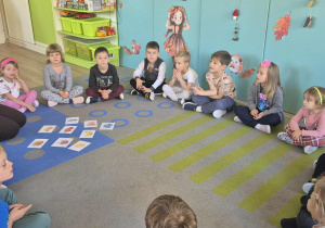 Nauczycielka pokazuje dzieciom ilustracje owoców.