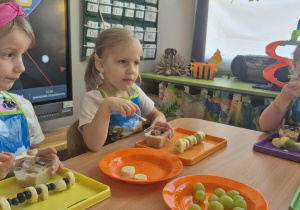 Dziewczynki jedzą mus owocowy.