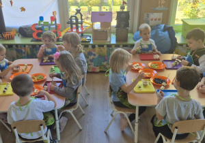 Dzieci jedzą szaszłyki owocowe.