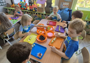 Dzieci robią szaszłyki owocowe.