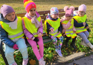 Dziewczynki siedzą na ławce w parku.