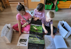 Dzieci oglądają kalendarz i kolorowankę.