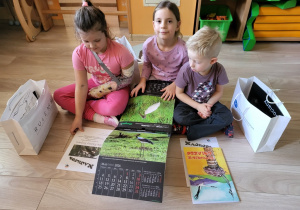 Dzieci oglądają kalendarz i kolorowankę.