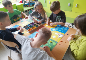 Dzieci ozdabiają kalosze plasteliną.