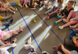 Dzieci siedzą w kole, na środku leży pantofelek Kopciuszka.