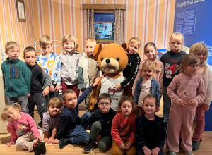Dzieci pozują do zdjęcia w makiecie domku misia Uszatka.