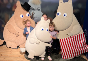 Dzieci pozują do zdjęcia na tle postaci z bajki o Muminkach.