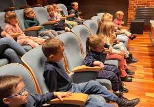 Dzieci siedzą w sali kinowej.