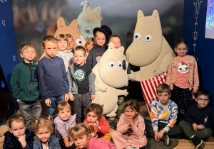 Dzieci pozują do zdjęcia na tle postaci z bajki o Muminkach.