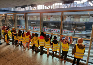 Dzieci igladają pociągi przez szybę.