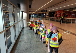 Dzieci ustawione w rzędzie, trzymają ilustracje.