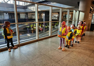 Dzieci ustawione w rzędzie, trzymają ilustracje.