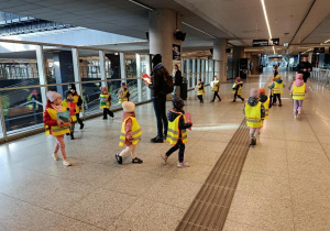 Dzieci idą w kole, trzymają ilustracje.