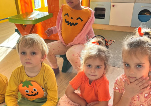 Dzieci w pomarańczowych strojach.