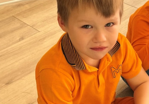 Chłopiec w pomarańczowym ubraniu.