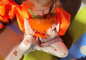 Dziewczynka wącha dynię.