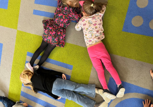 Dzieci na dywanie ze swoich ciał ułozyły trójkąt.