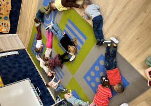 Dzieci na dywanie ze swoich ciał ułozyły koło.