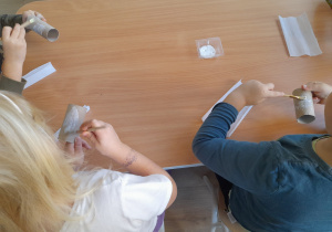 Dzieci smarują rolkę klejem.