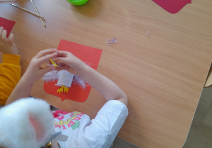 Dziecko przykleja elementy do pracy.