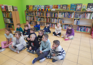 Dzieci siedzą w bibliotece.