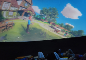 Dzieci leżą w środku kopuły planetarium, oglądają wyświetlaną animację.