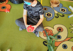 Dziecko rozpoznaje warzywo po dotyku. Przed nim leżą warzywa.