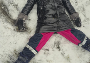 Dziewczynka wykonuje aniołka na śniegu.