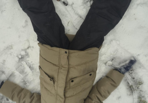 Chłopiec wykonuje aniołka na śniegu.