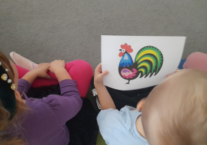 Dzieci oglądają ilustrację łowickiego kogutka.