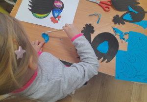 Dziewczynka smaruje klejem element.