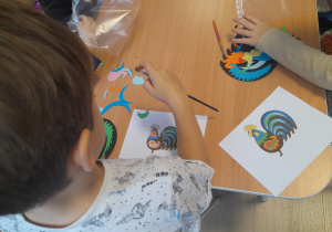 Chłopiec tworzy swojego łowickiego kogutka.