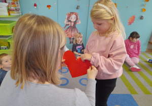 Dziewczynka przebija papierowe srece pinezką.