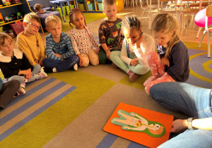 Dzieci oglądają obrazek z układem pokarmowym człowieka.