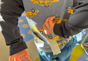 Chłopiec z przyklejoną taśmą na plecach.