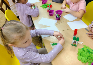 Dzieci wyklejają choinki.