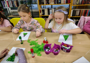Dzieci wyklejają choinki.