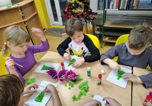 Dzieci wyklejają choinki.