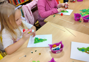 Dzieci wyklejają choinki.