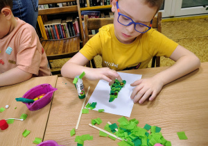 Dzieci wyklejają choinki.